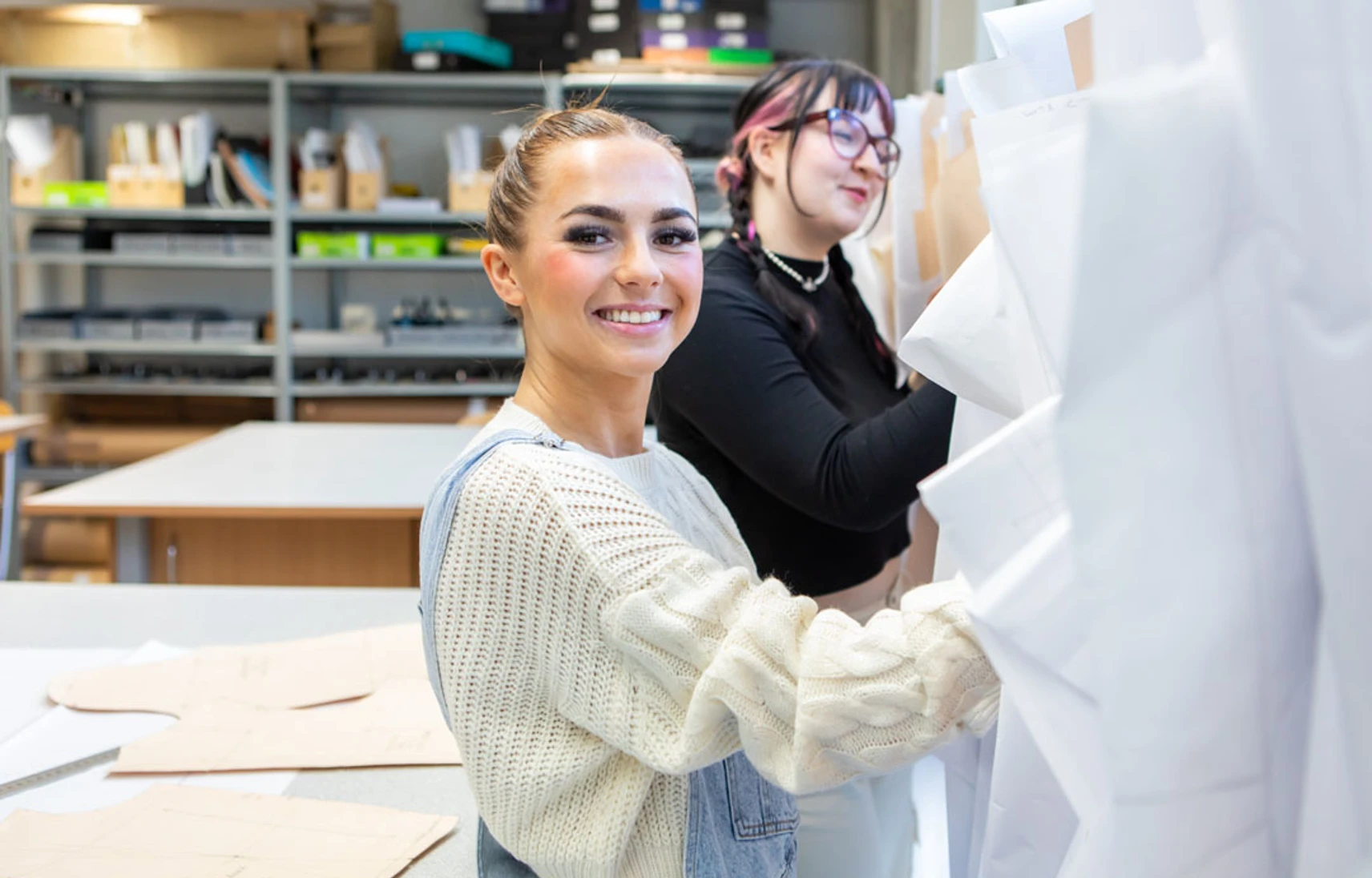Two fashion students organizing and selecting design patterns in a creative workspace. Two fashion students organizing and selecting design patterns in a creative workspace.